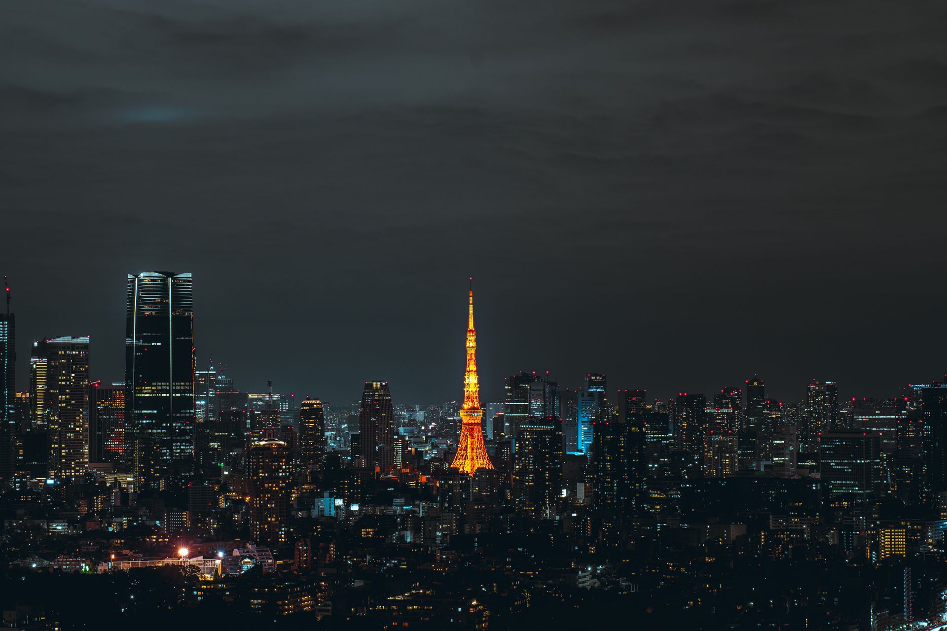 Tokyo Tower illuminated in amber at night, photographed by Szymon Shields