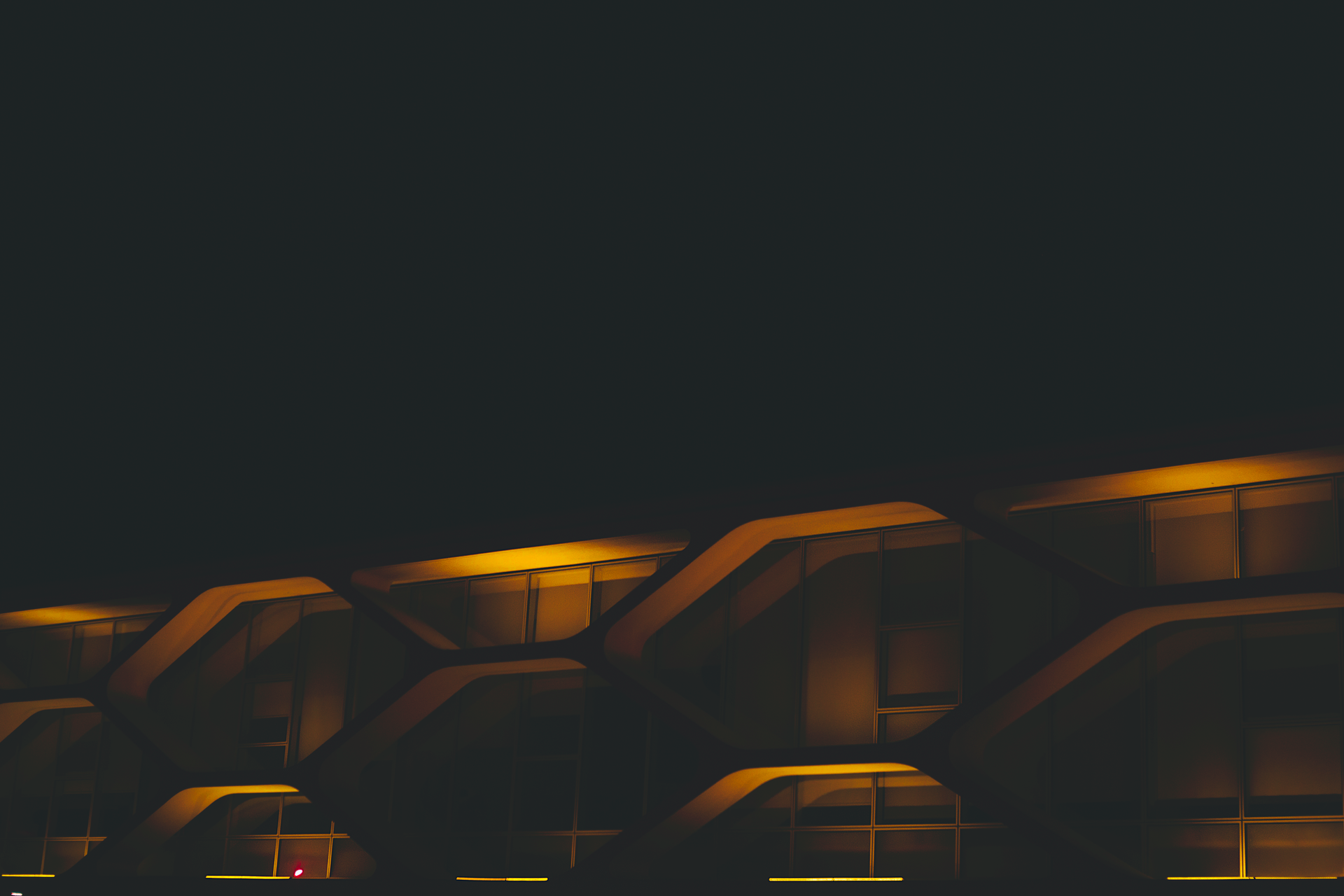 Dark modern architecture lit in amber at night, photographed by Jo&atilde;o Jesus